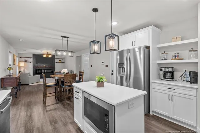 a kitchen with stainless steel appliances a dining table chairs stove refrigerator and cabinets