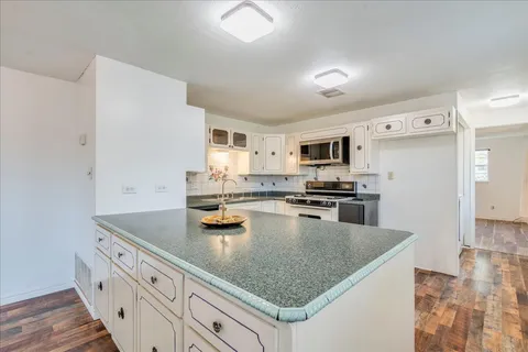 a kitchen with stainless steel appliances granite countertop a sink dishwasher stove and refrigerator with wooden floor