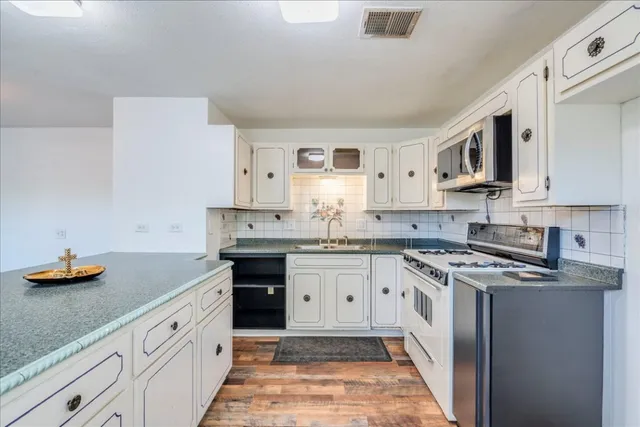 a kitchen with stainless steel appliances granite countertop a sink stove and cabinets