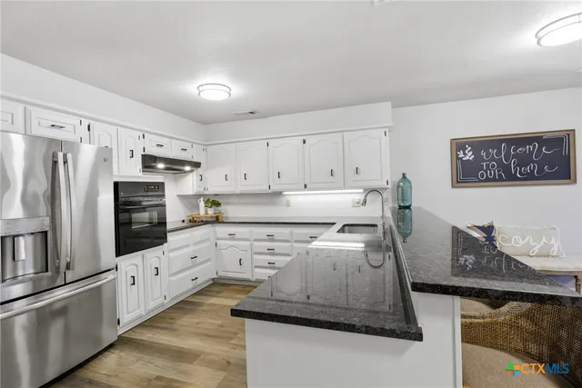 a kitchen with granite countertop white cabinets and white appliances