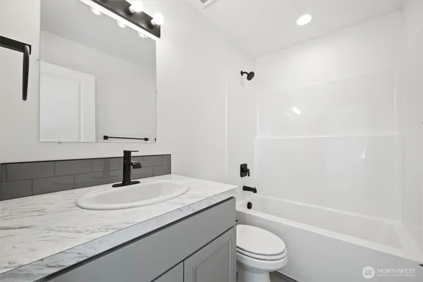 a bathroom with a granite countertop sink a toilet and shower