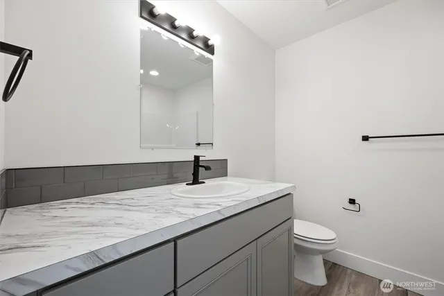 a bathroom with a granite countertop sink a toilet and a mirror