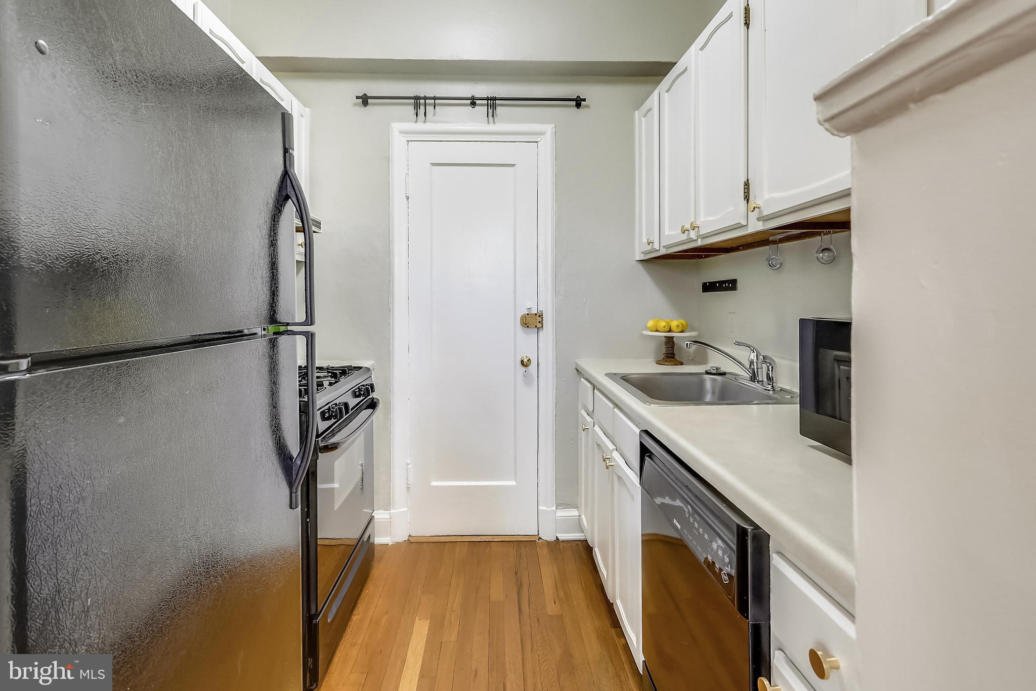 2032 Belmont Road Northwest, Unit 414 Washington, DC 20009 - Photo 14 of 31 Galley kitchen with white cabinetry