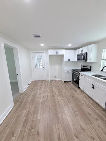 a large kitchen with a wooden floor and white stainless steel appliances