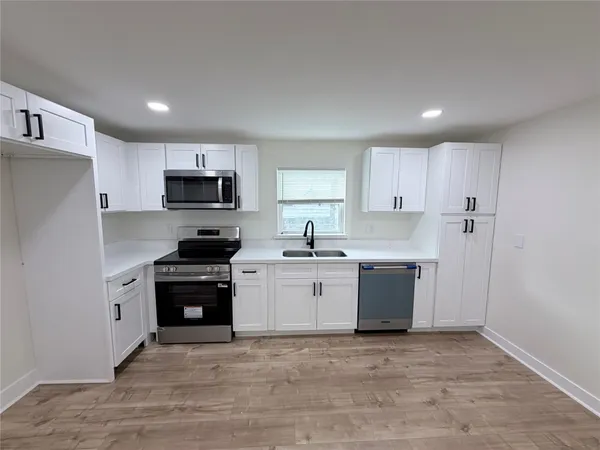 a kitchen with granite countertop a refrigerator stove top oven and sink