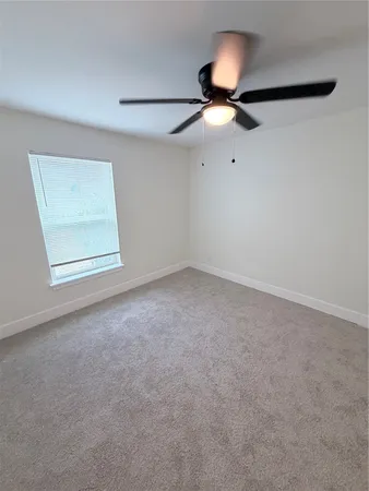 an empty room with a ceiling fan and a window