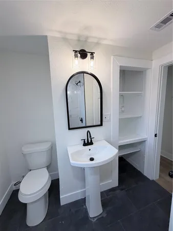 a bathroom with a toilet sink and mirror