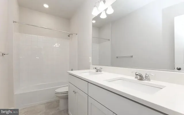 a bathroom with a granite countertop sink a toilet and shower
