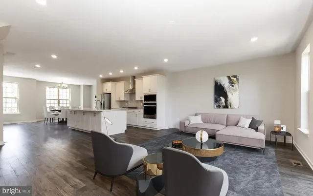a living room with furniture kitchen view and a wooden floor