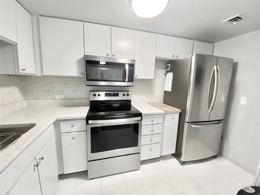 a kitchen with stainless steel appliances white cabinets white stove a microwave and a refrigerator