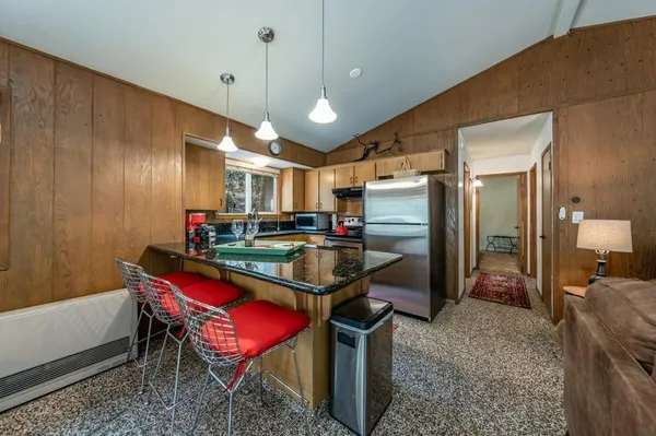 a kitchen with stainless steel appliances kitchen island granite countertop a refrigerator a stove a sink dishwasher and a dining table with wooden floor