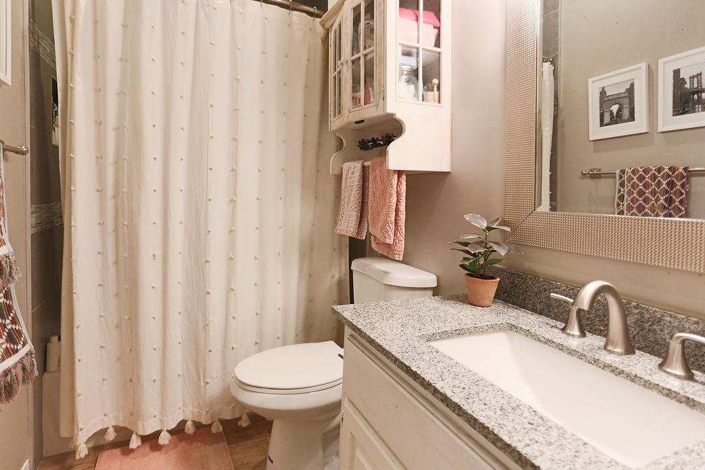 1307 Kinney Avenue, Unit 121 Austin, TX 78704 - Photo 8 of 12 a bathroom with a granite countertop sink and a toilet