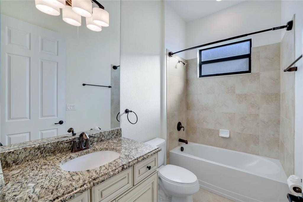2806 Aviamar Circle Naples, FL 34114 - Photo 22 of 50 a bathroom with a granite countertop sink a toilet a mirror a bathtub and shower
