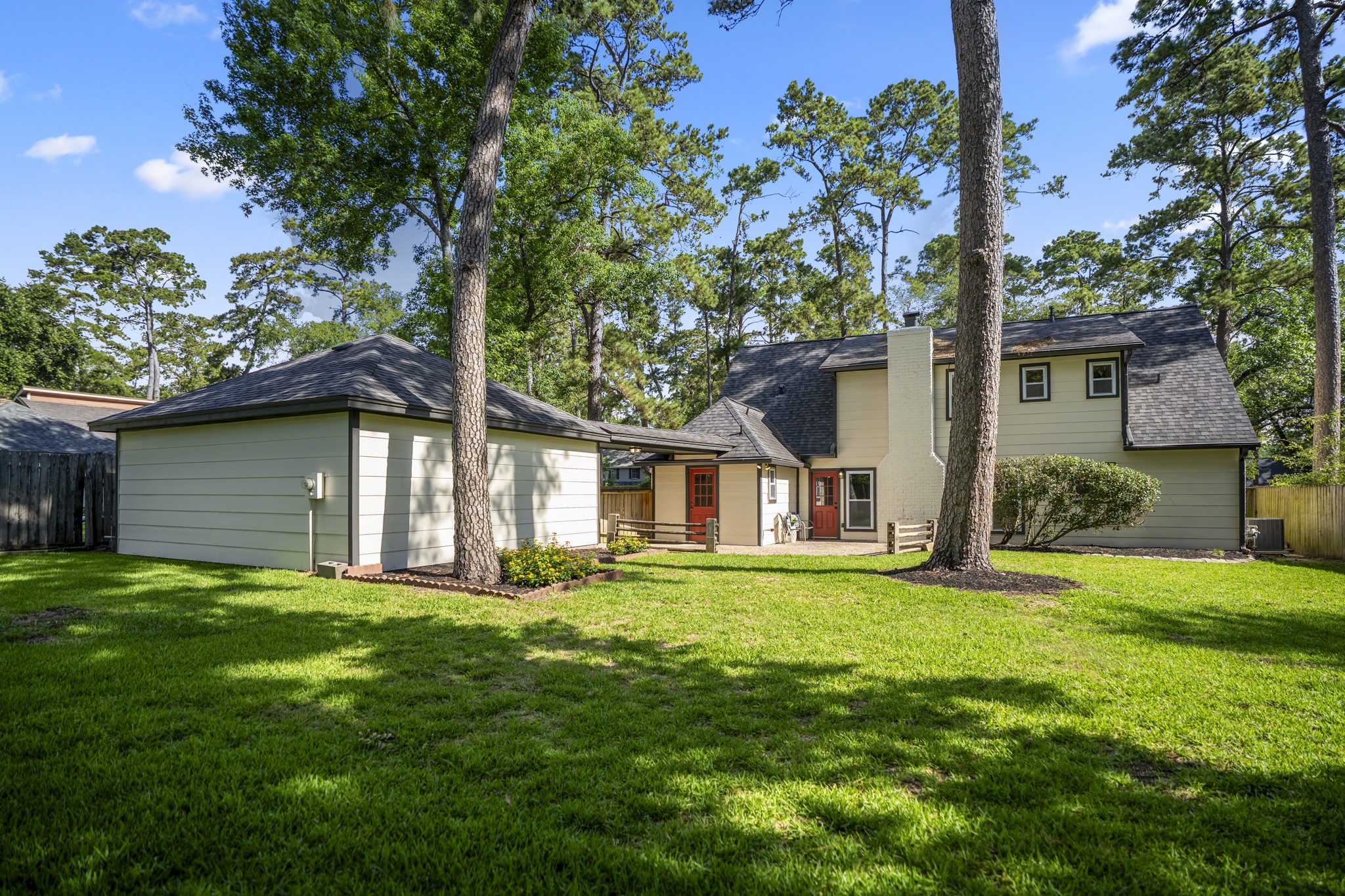 6303 Larkmount Drive Spring, TX 77389 - Photo 43 of 50 Pulling back a little farther, the full backyard setting starts to come together — green space stretching across the lot, mature trees offering shade, and the refreshed exterior tying the home and detached garage into one cohesive outdoor scene. It feels like a backyard with room to breathe, relax, and enjoy the Northampton setting.
