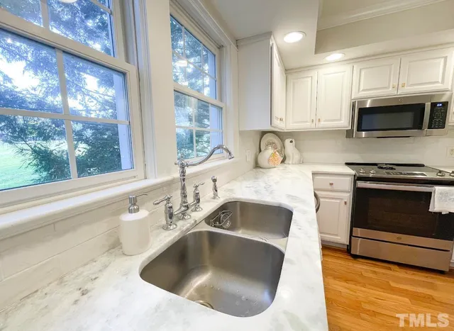 a kitchen with granite countertop white cabinets and stainless steel appliances