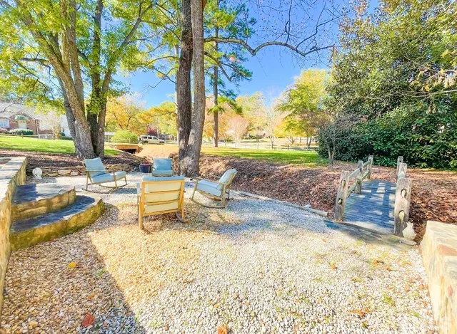 a view of a backyard with large trees and wooden fence
