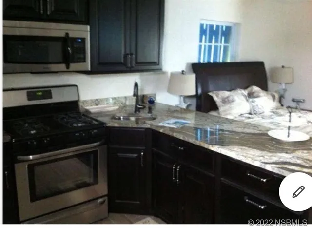 a kitchen with stainless steel appliances granite countertop a stove a sink and a microwave