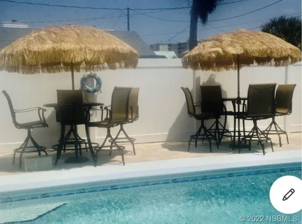 a view of outdoor dining space with a table and chairs under an umbrella with a small yard