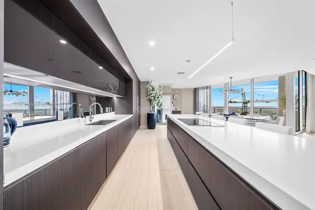 a large white kitchen with stainless steel appliances kitchen island a large counter top a stove and a sink