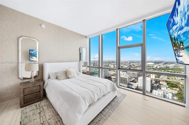a bedroom with bed and a large mirror next to a window