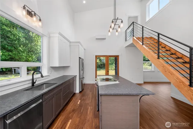 a kitchen with stainless steel appliances granite countertop a sink a stove and a wooden floors