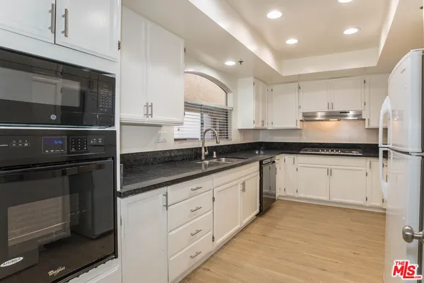 a kitchen with granite countertop white cabinets and stainless steel appliances