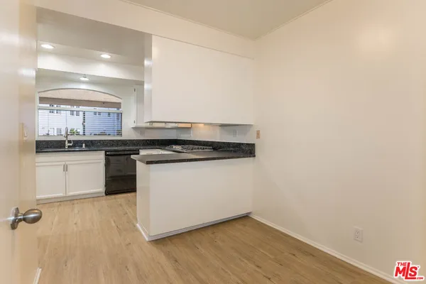 a kitchen with a white cabinets and wooden floor