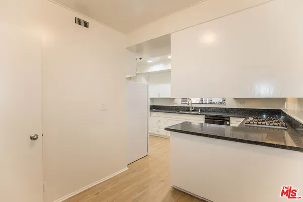 a kitchen with a sink and a stove with wooden floor
