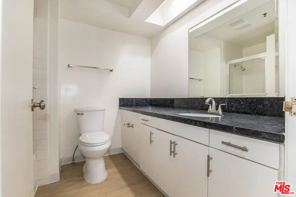 a bathroom with a granite countertop sink a toilet and a mirror
