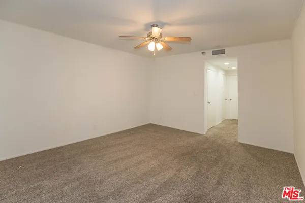 an empty room with a chandelier fan and windows