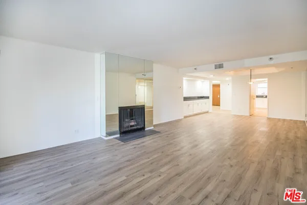 a view of empty room with wooden floor and fireplace