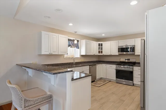 a kitchen with stainless steel appliances granite countertop a stove top oven a sink dishwasher and a refrigerator with wooden cabinets