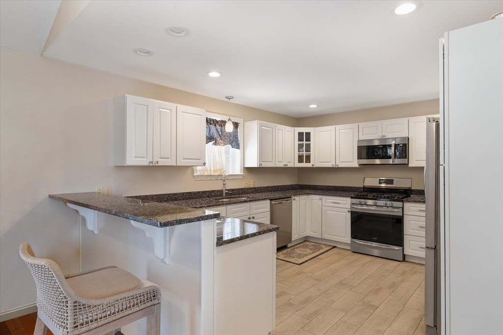 77 Old Keene Road Athol, MA 01331 - Photo 8 of 31 a kitchen with stainless steel appliances granite countertop a stove top oven a sink dishwasher and a refrigerator with wooden cabinets