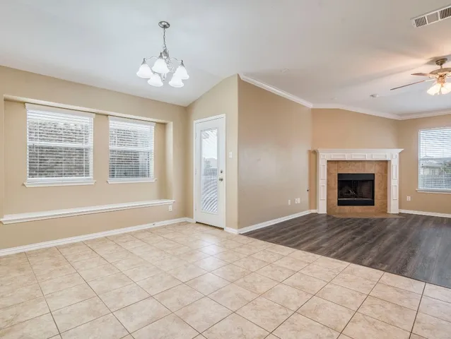 an empty room with windows chandelier fan and fireplace
