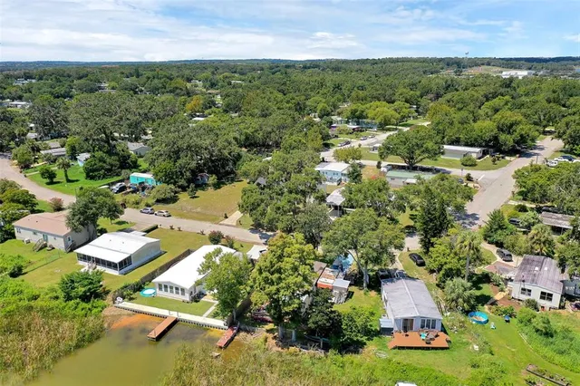 an aerial view of residential houses with outdoor space and trees all around