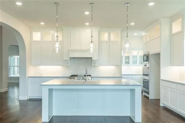 a kitchen with kitchen island granite countertop a sink a counter space appliances and cabinets