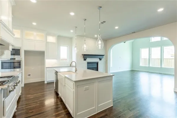 a large kitchen with stainless steel appliances kitchen island a large counter top and a wooden floors