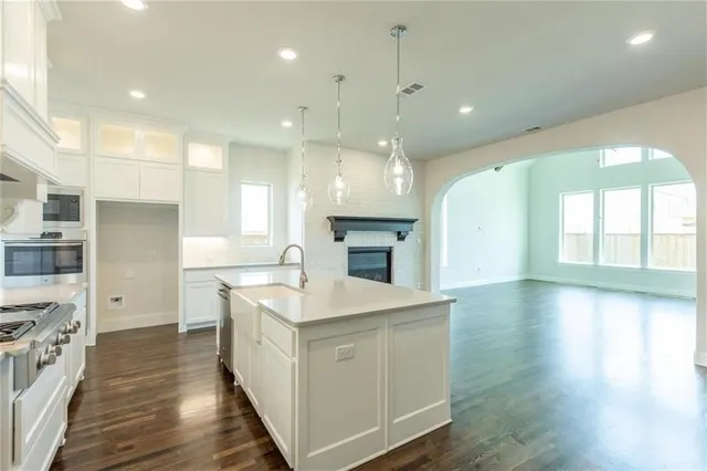 a large kitchen with stainless steel appliances kitchen island a large counter top and a wooden floors