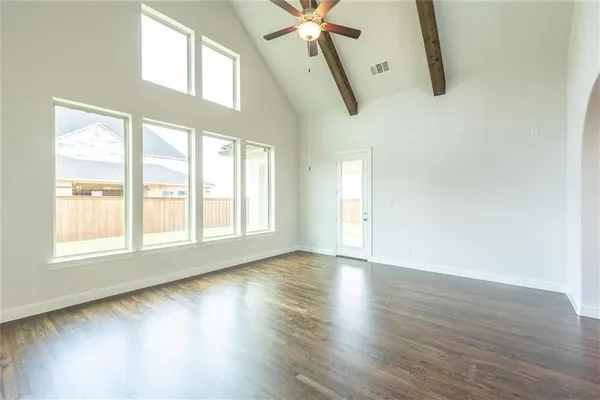an empty room with wooden floor fan and windows