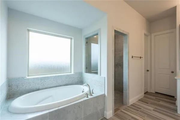 a white bath tub sitting in a bathroom near shower