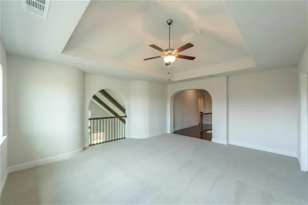 an empty room with chandelier fan and windows
