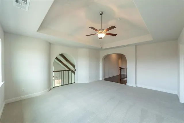 an empty room with chandelier fan and windows
