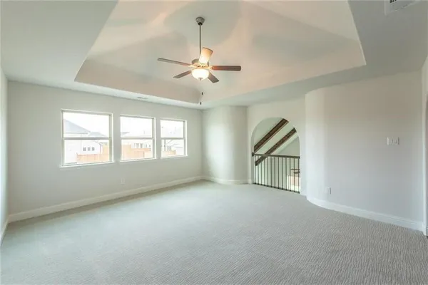 an empty room with chandelier fan and windows
