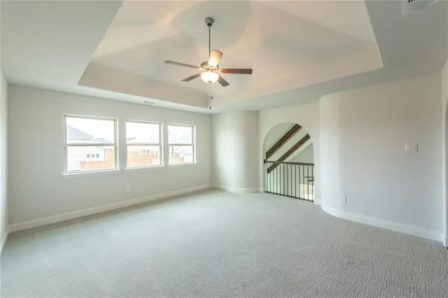 an empty room with chandelier fan and windows