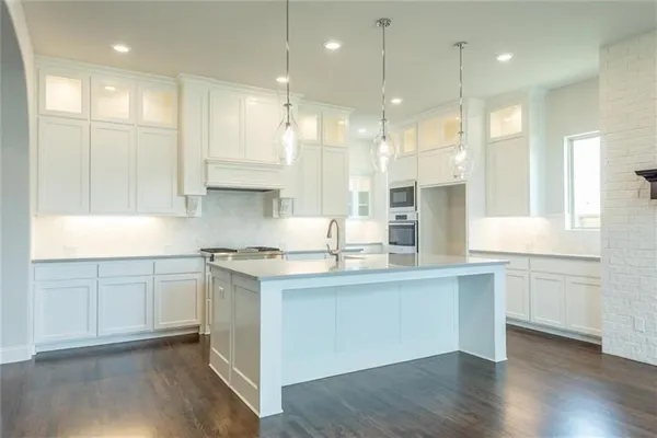 a kitchen with stainless steel appliances granite countertop a sink a stove a refrigerator and white cabinets