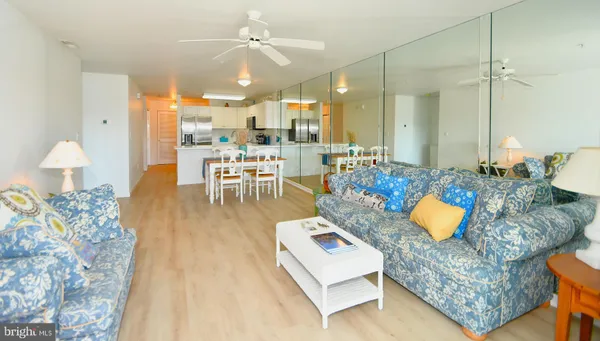 a living room with couches and kitchen view with wooden floor