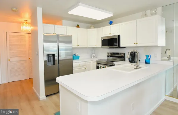 a kitchen with stainless steel appliances a refrigerator a sink a stove top oven a counter space and cabinets