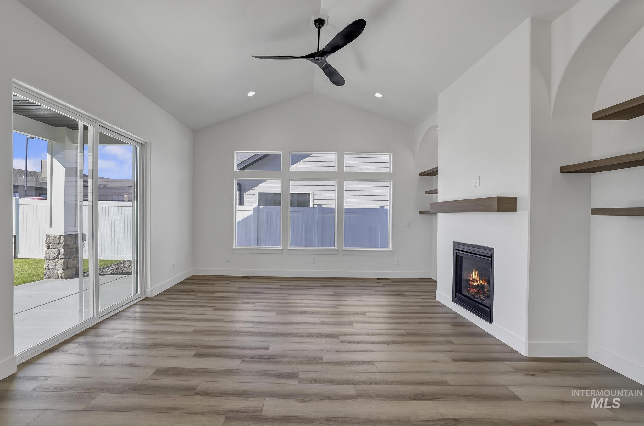 521 Falling Leaf Lane Twin Falls, ID 83301 - Photo 11 of 42 Unfurnished living room with vaulted ceiling, plenty of natural light, light wood-style floors, a glass covered fireplace, and a ceiling fan