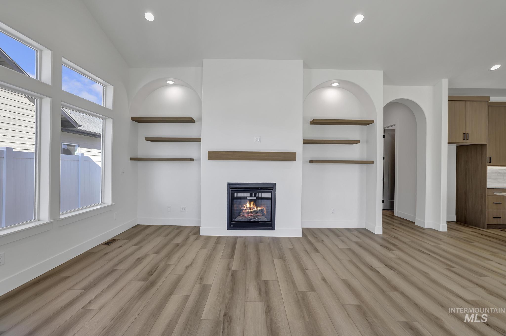 521 Falling Leaf Lane Twin Falls, ID 83301 - Photo 12 of 42 Unfurnished living room with recessed lighting, light wood finished floors, arched walkways, and a glass covered fireplace
