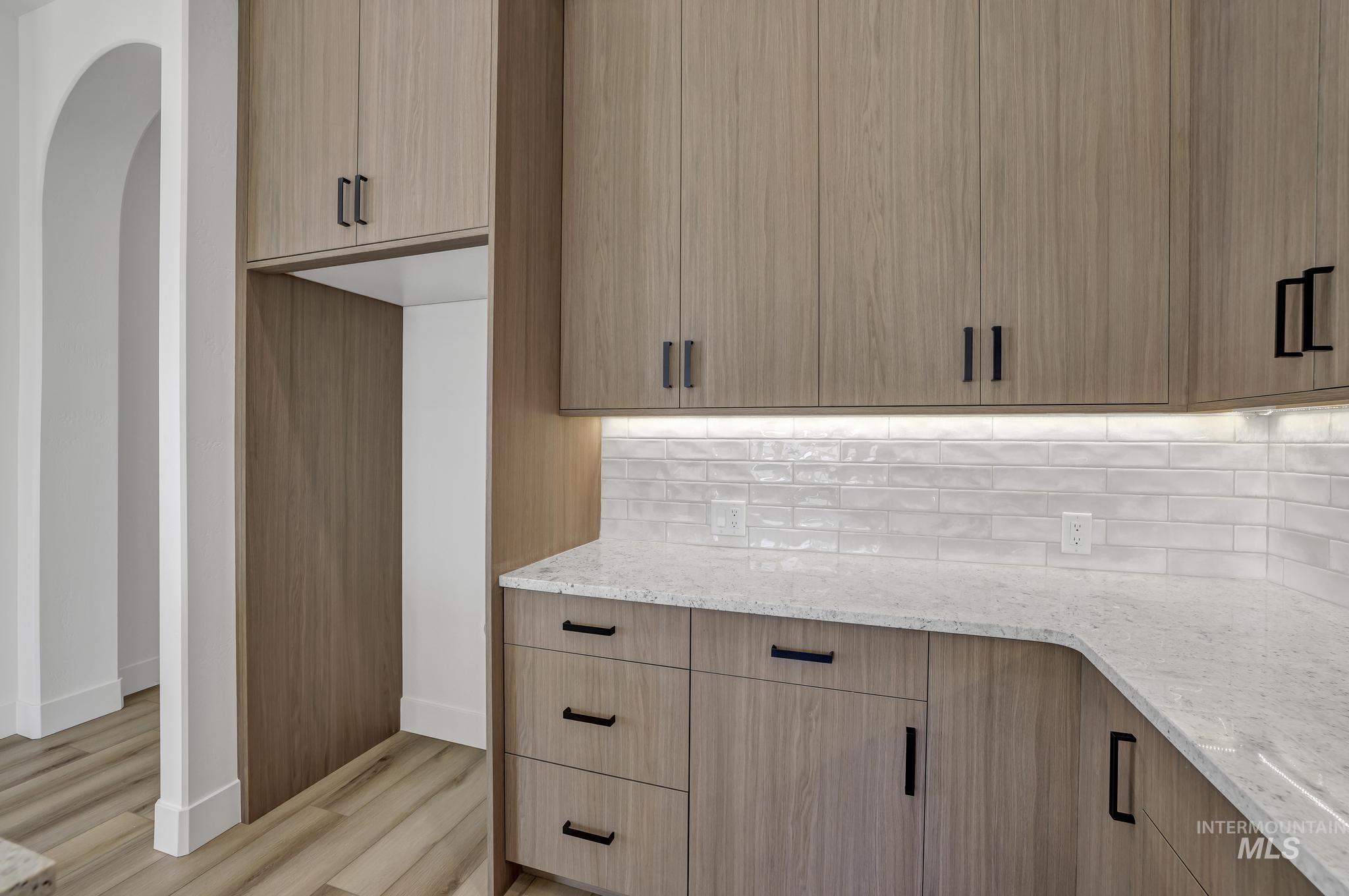 521 Falling Leaf Lane Twin Falls, ID 83301 - Photo 17 of 42 Kitchen with light stone counters, light wood finished floors, decorative backsplash, modern cabinets, and light brown cabinets